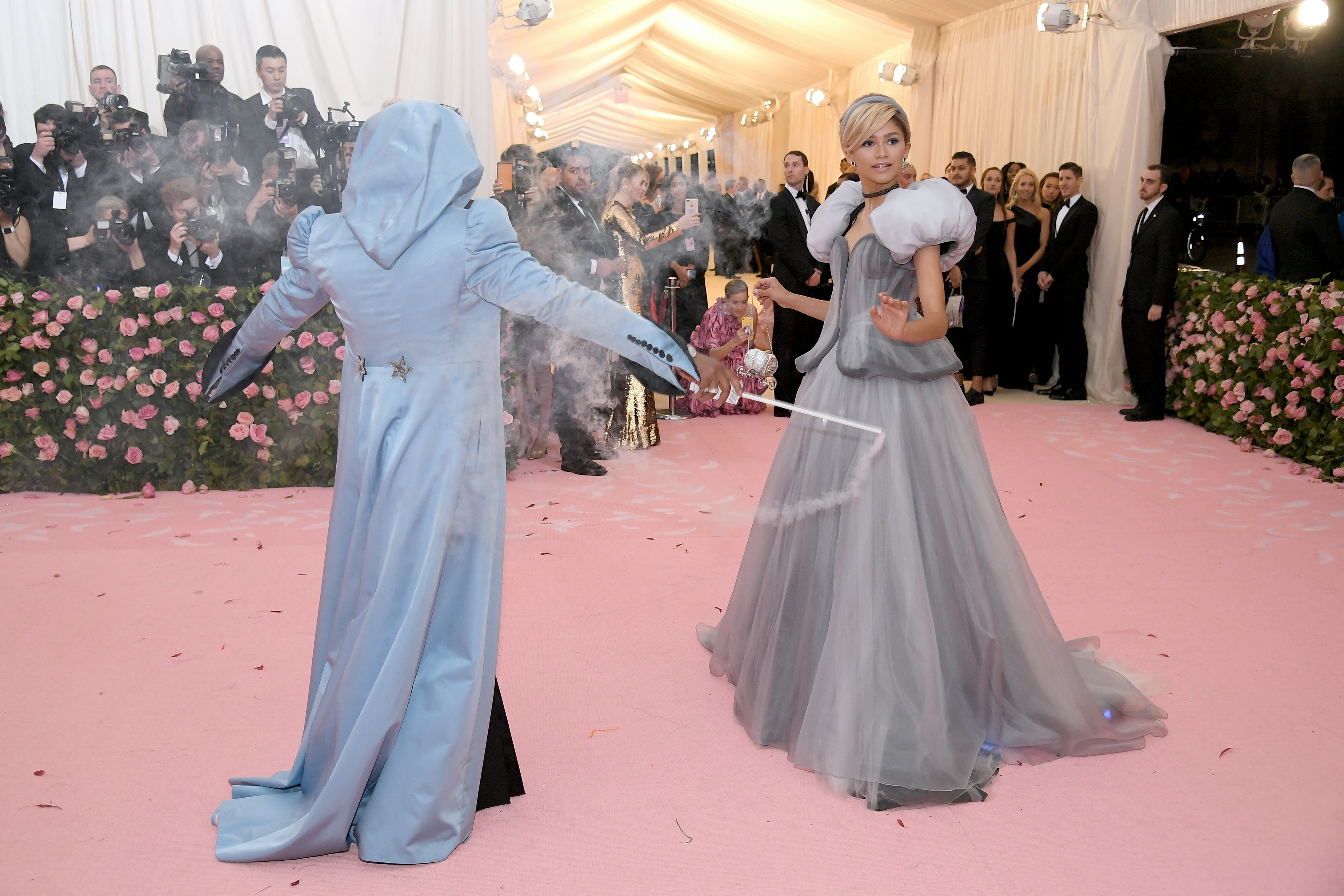 Zendaya dressed in a Cinderella-inspired gown with Law Roach dressed as her Fairy Godmother wielding a wand to transform the dress