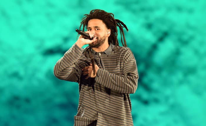J. Cole on stage performing with microphone, dressed in striped attire, with a dynamic backdrop
