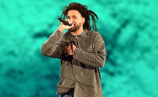 J. Cole on stage performing with microphone, dressed in striped attire, with a dynamic backdrop
