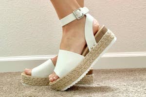 Person's feet in white platform sandals with espadrille soles