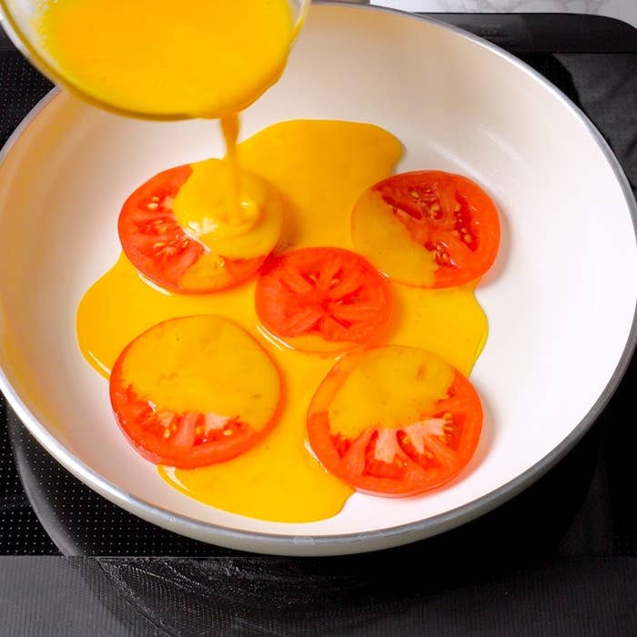 スライスしたトマトの上に卵を流し入れる様子