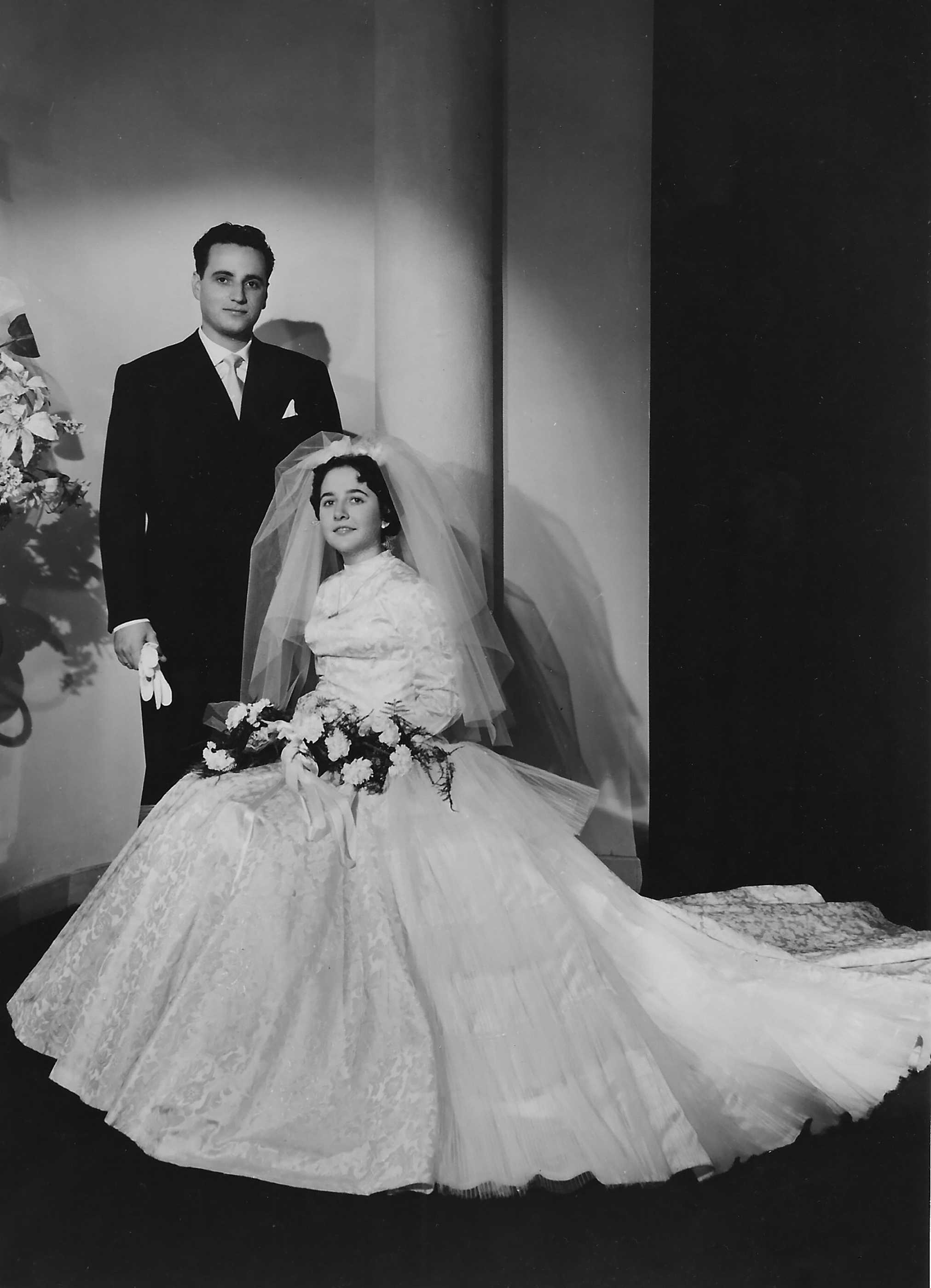 Bride in a full gown with a veil and groom in a suit, both posing for a classic wedding photo