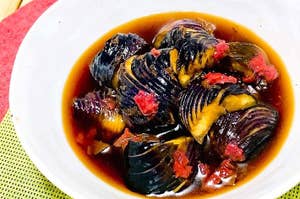 黒い殻の貝と赤い具材が入ったスープの料理です。
