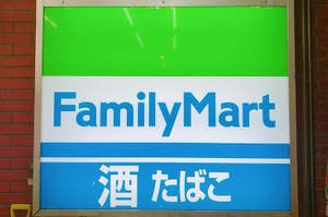 ファミリーマートの看板、緑と青のロゴに店名と日本語で「満たされて」の文字。