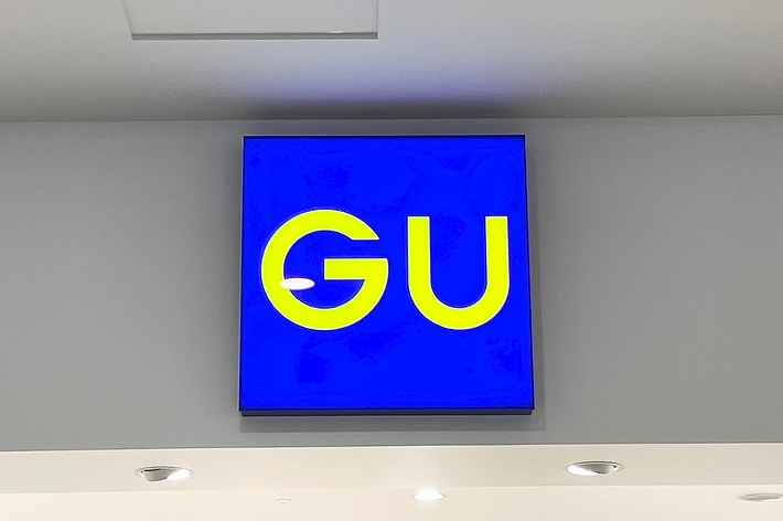 Sign with the letters &ldquo;GU&rdquo; on a blue background, mounted on a wall above a doorway