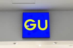 Sign with the letters "GU" on a blue background, mounted on a wall above a doorway