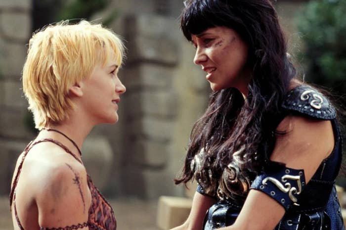Two characters from Xena: Warrior Princess, Gabrielle and Xena, face each other with intense expressions