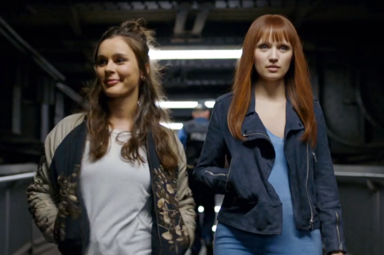 Two women walking side by side in a dimly lit corridor