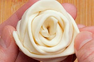手作りの白いバラの形をした飾りが手に持たれています。