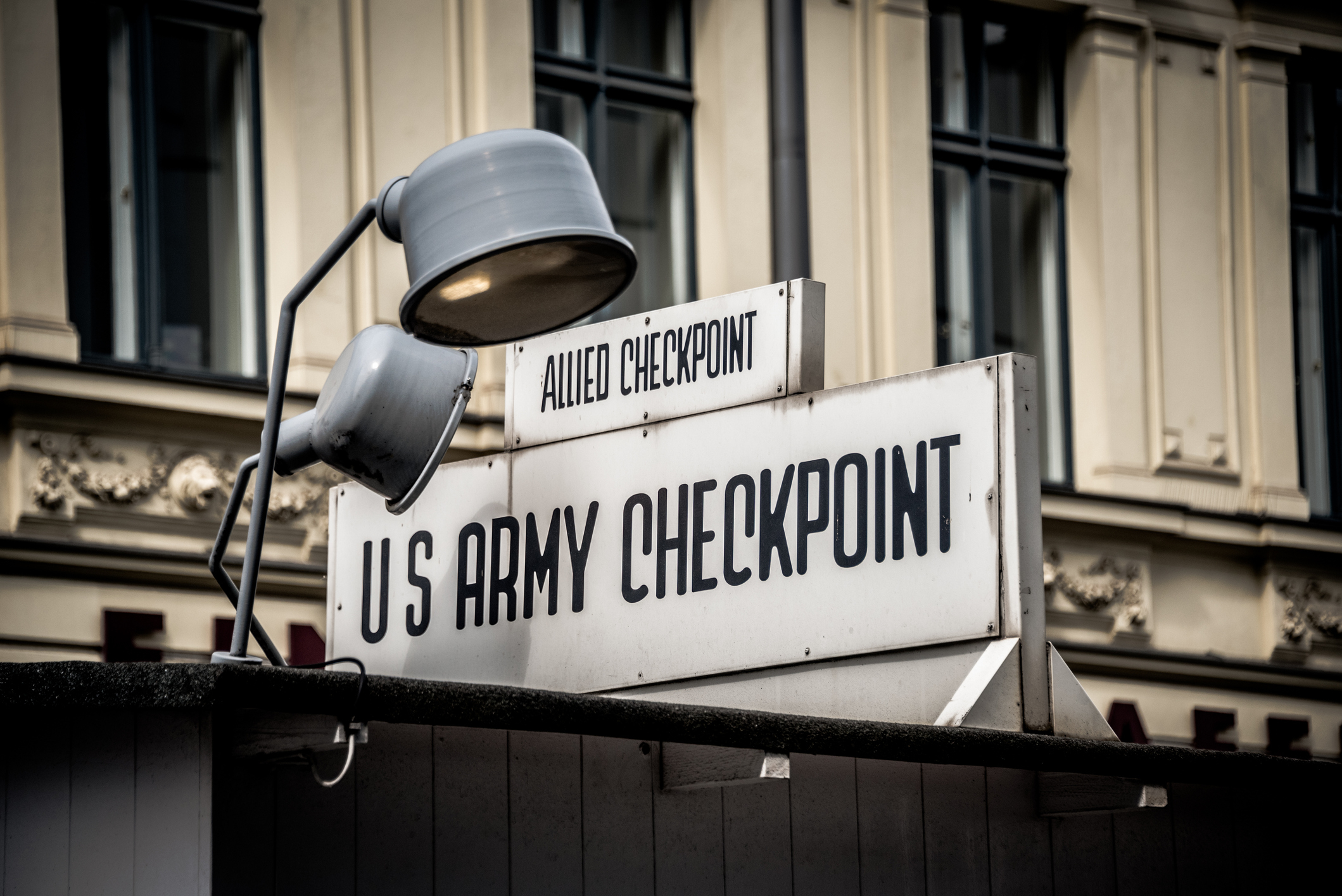 Sign reading &quot;Allied Checkpoint&quot; above and &quot;U.S. Army Checkpoint&quot; below on a building with a lamp overhead