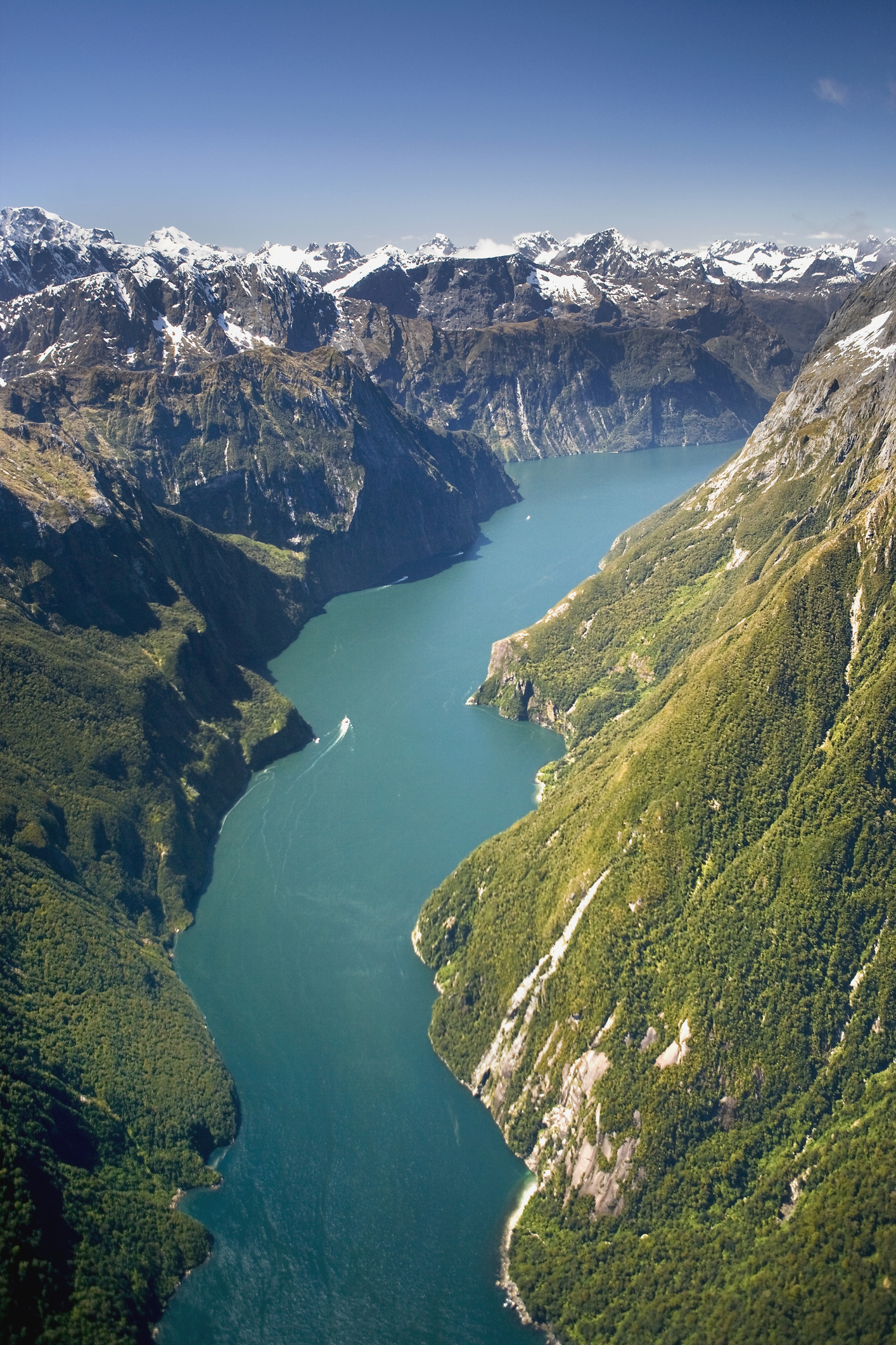 Aerial view of a fjord with steep cliffs and snowy mountain peaks
