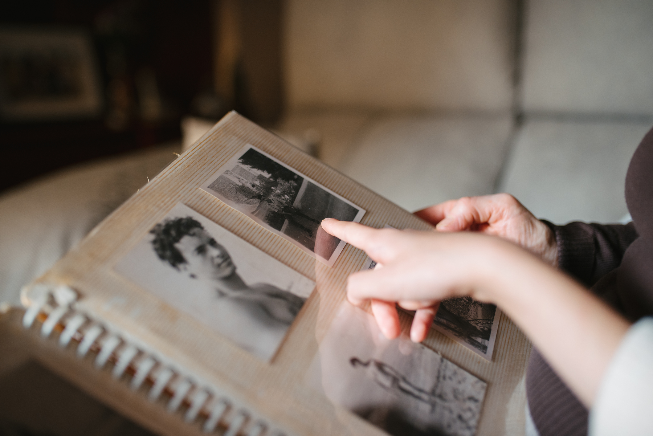 Person&#x27;s hands turning pages of an old photo album with black-and-white pictures