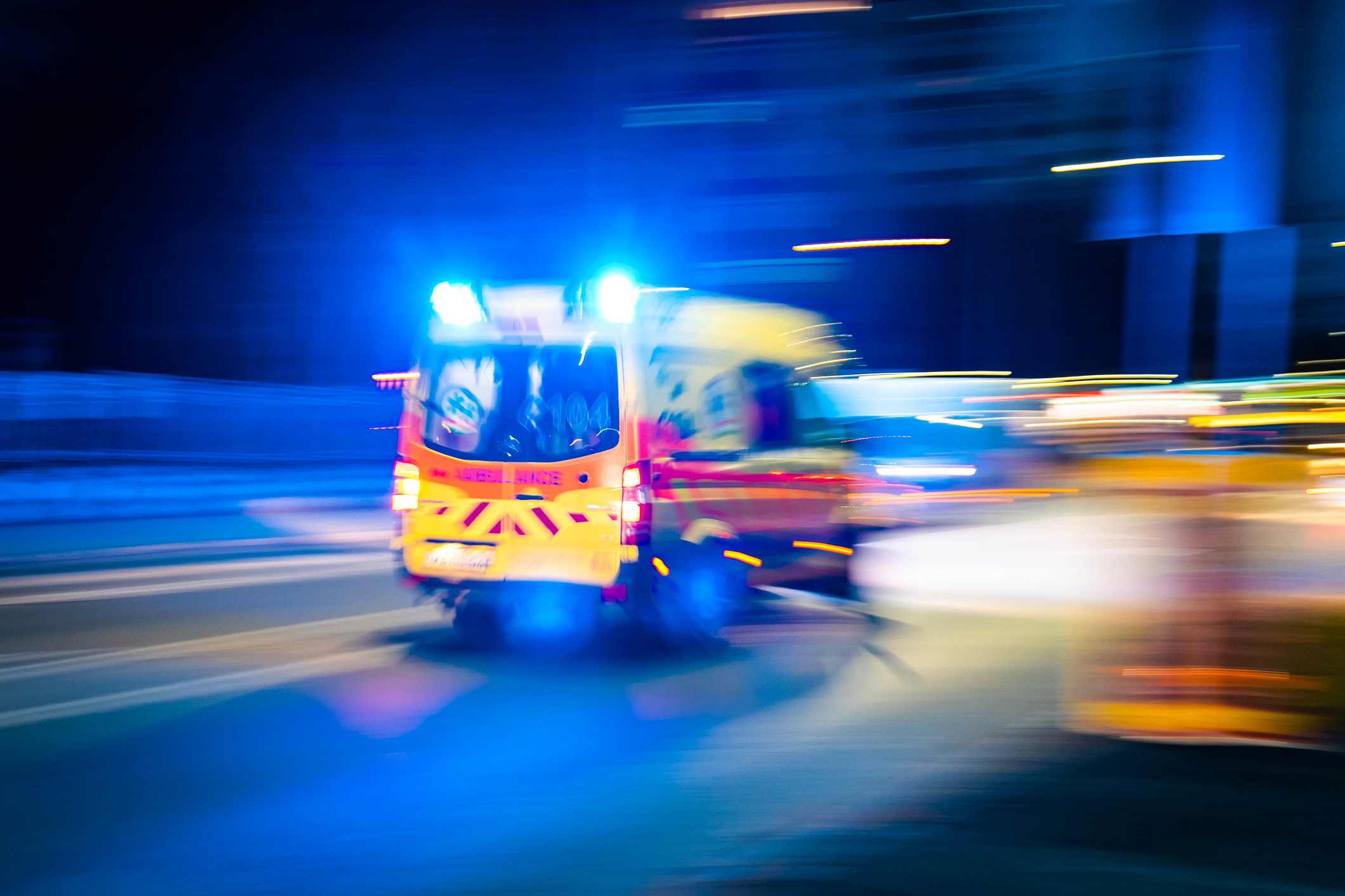Blurred image of a moving ambulance with its emergency lights on at nighttime