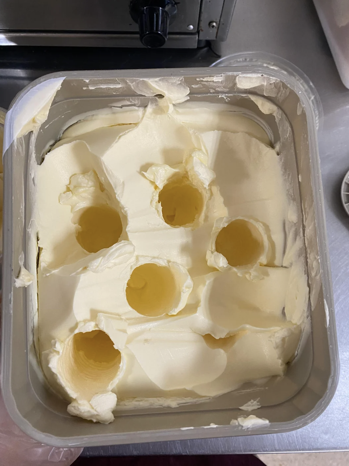 Top view of a container of softened ice cream with several scoops removed