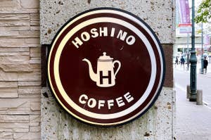 星野コーヒーの看板。ティーポットのロゴが特徴。街中の壁に取り付けられている。