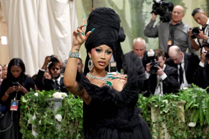 Cardi B poses with a towering updo and extravagant black gown, accessorized with sparkling jewelry