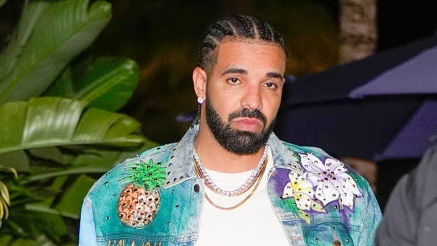 Drake in a denim jacket with pineapple and flower designs, looking serious