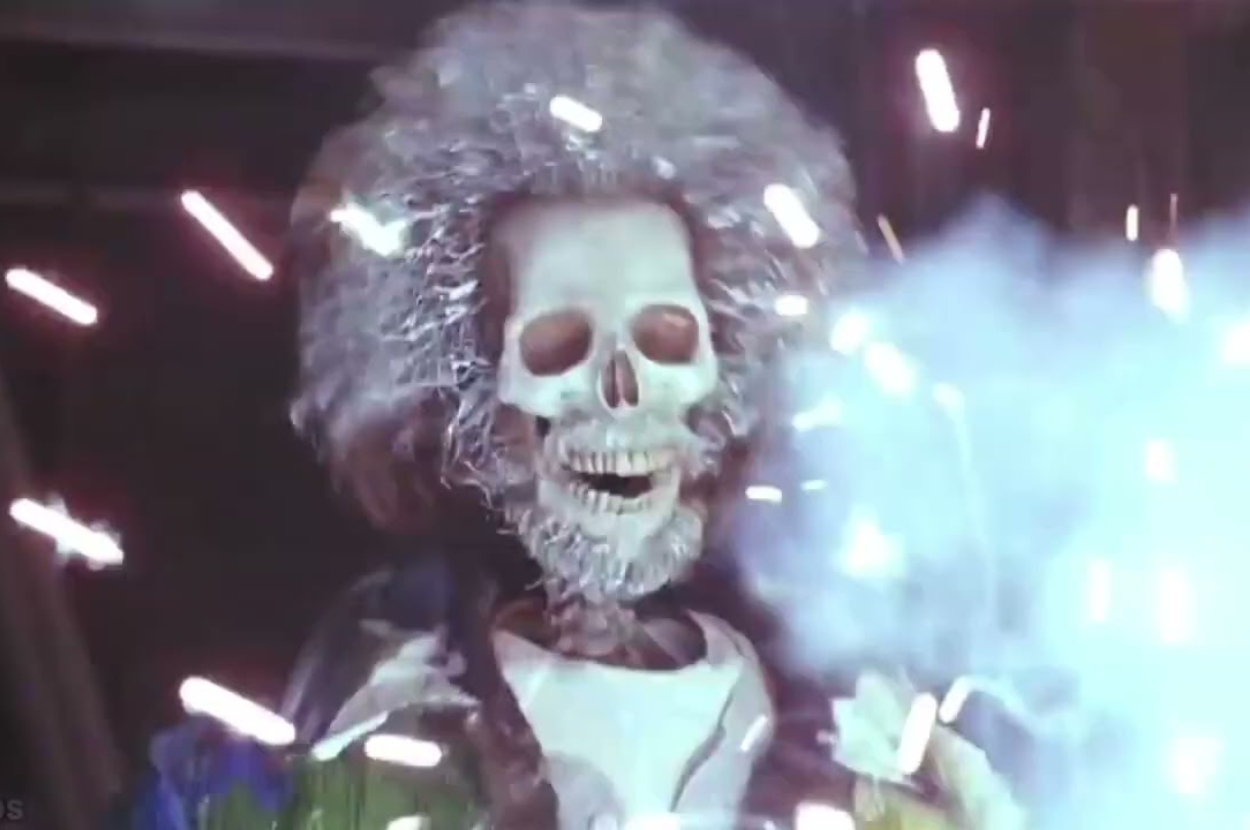 Skeleton figure with frizzy hair holding a sparkler, illuminated and celebratory