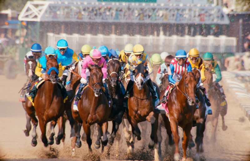 Jockeys on horses racing on a dirt track, suggesting competition and speed