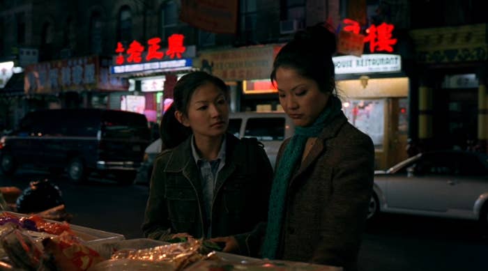 Two women standing by a street market at night with illuminated signs in the background