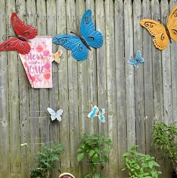 Garden wall with a variety of butterfly decorations and a "Bless Our Home" sign