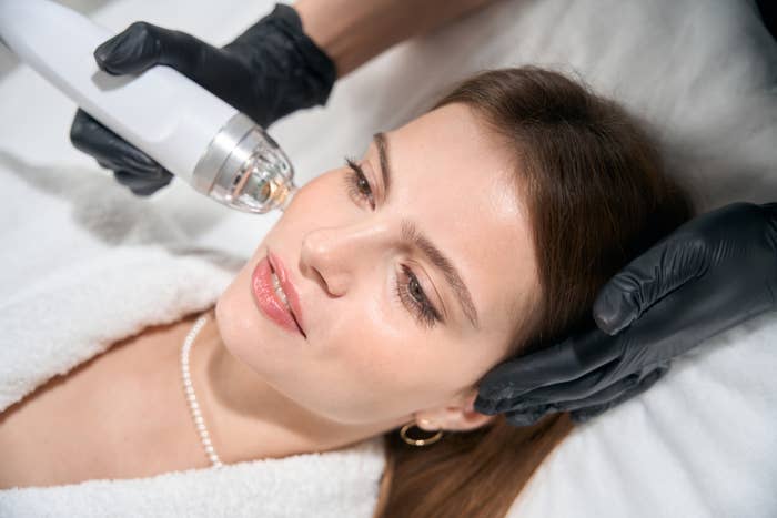 Woman receiving a facial treatment with a specialized device at a spa