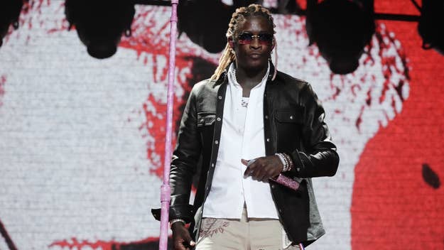 Young Thug performs onstage with microphone, wearing a leather jacket and sunglasses