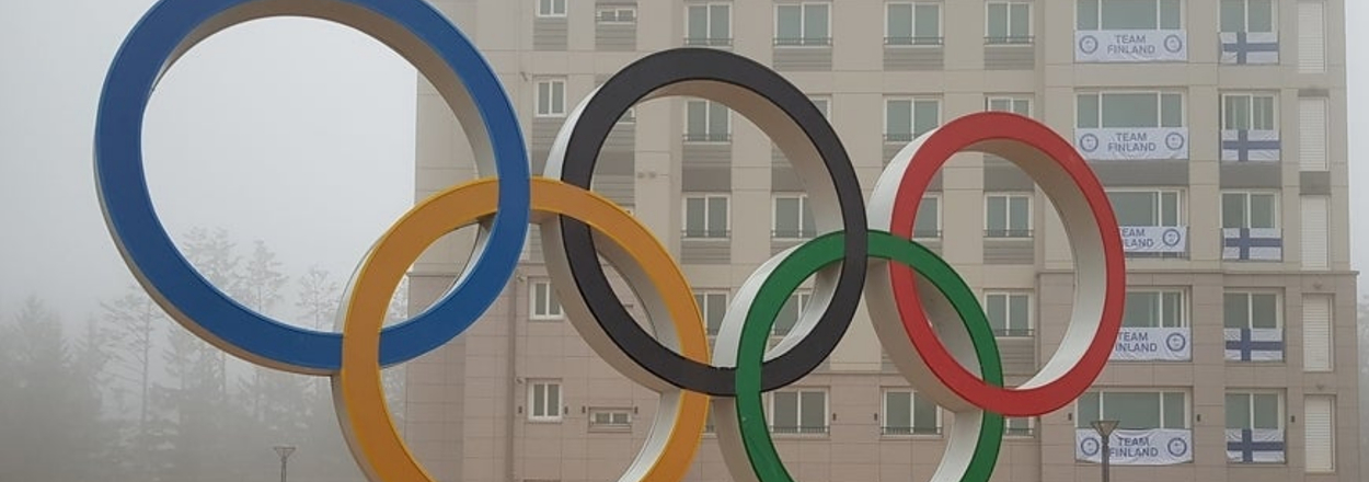 Person standing in front of Olympic Rings at a foggy Olympic Village