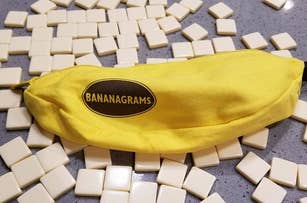 Yellow Bananagrams pouch with scattered letter tiles on a surface, used for word game enthusiasts