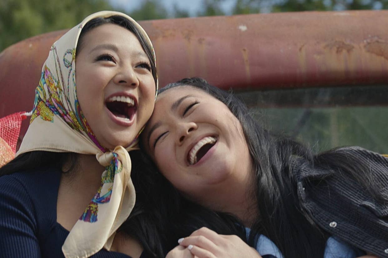 Two women laughing together, one wearing a headscarf. Expressions of joy and friendship