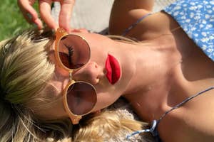 Person in sunglasses lying down, red lipstick visible, no identifiable features to name
