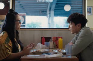 Two individuals sitting opposite each other at a diner table, engaged in conversation