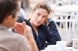 Woman with a pensive expression sitting at a cafe table, conversing with an unseen person