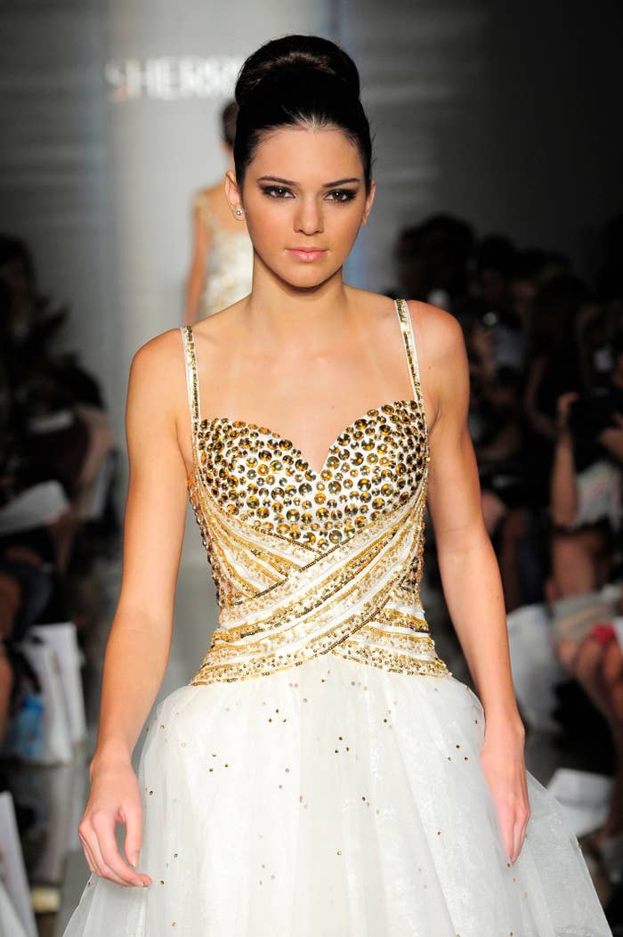 Kendall Jenner walks runway in a gold and white dress with a sequined bodice