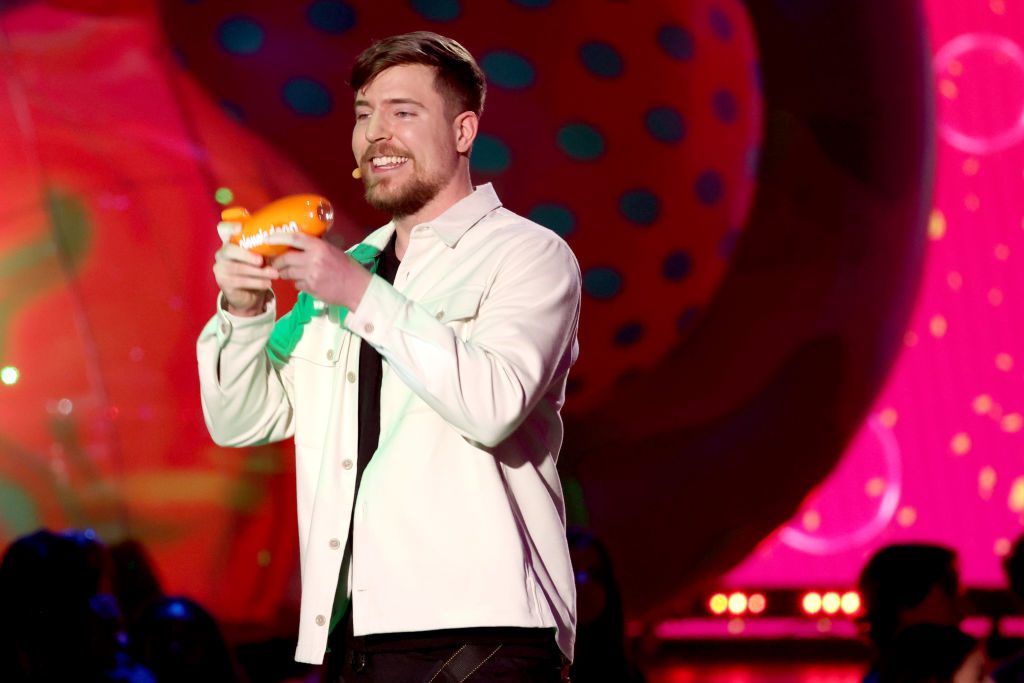 Mr. Beast on stage smiling and holding an award, with colorful backdrop