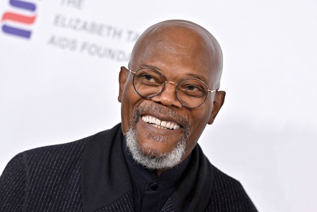 Samuel L. Jackson smiling in a black turtleneck and glasses at an event