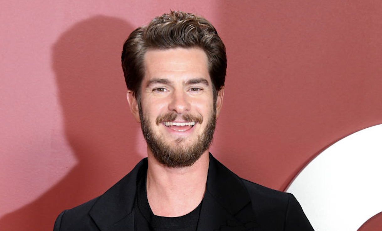 Andrew Garfield smiling in a classic black suit at an event