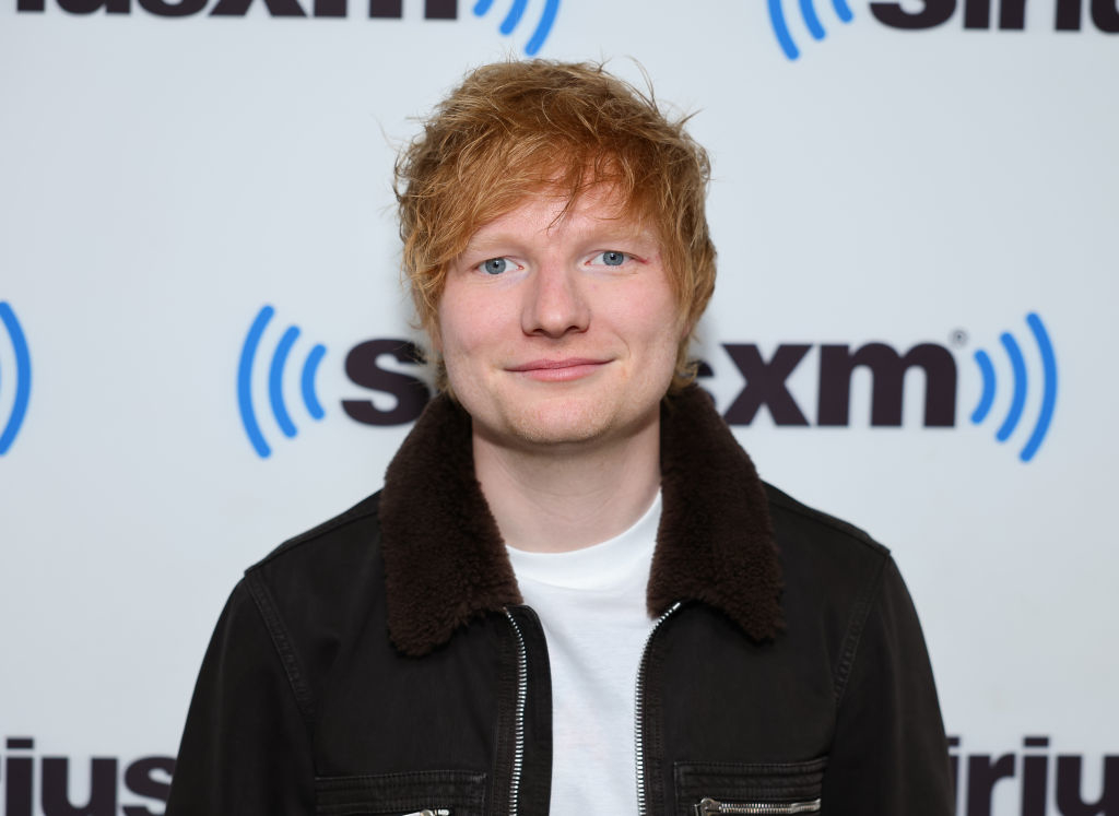 Ed Sheeran in a black jacket standing in front of a SiriusXM backdrop