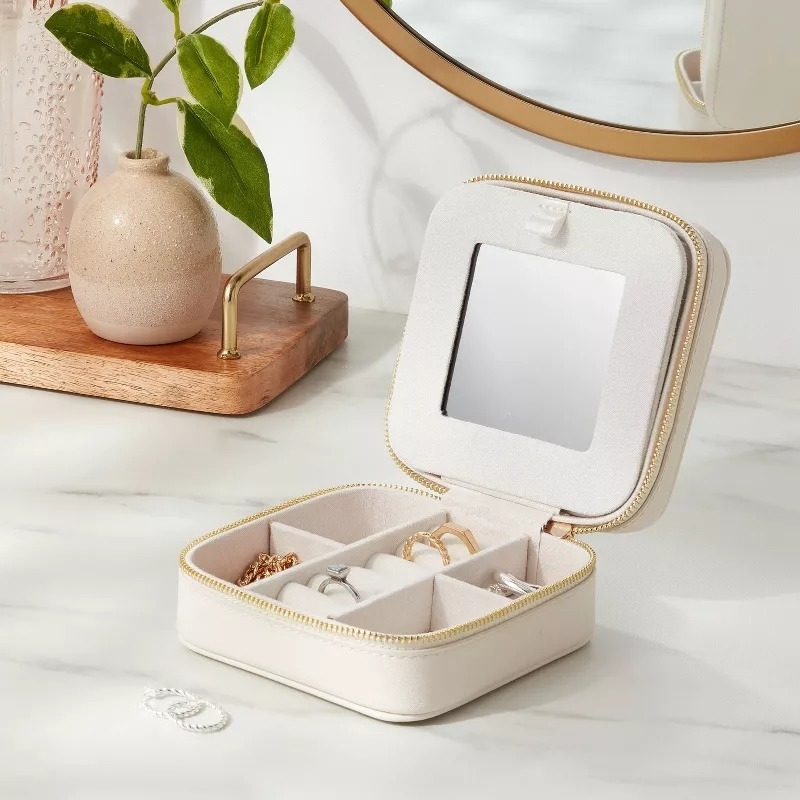 A portable jewelry case with compartments for accessories, displayed on a vanity