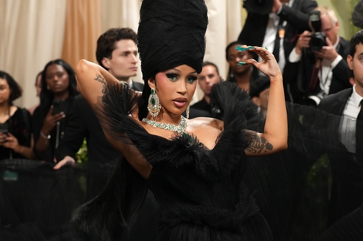 A person wearing an elaborate feathered outfit with a dramatic headpiece posing at an event