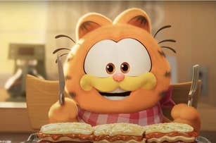 Animated character Garfield with a fork and knife in front of a stack of lasagna