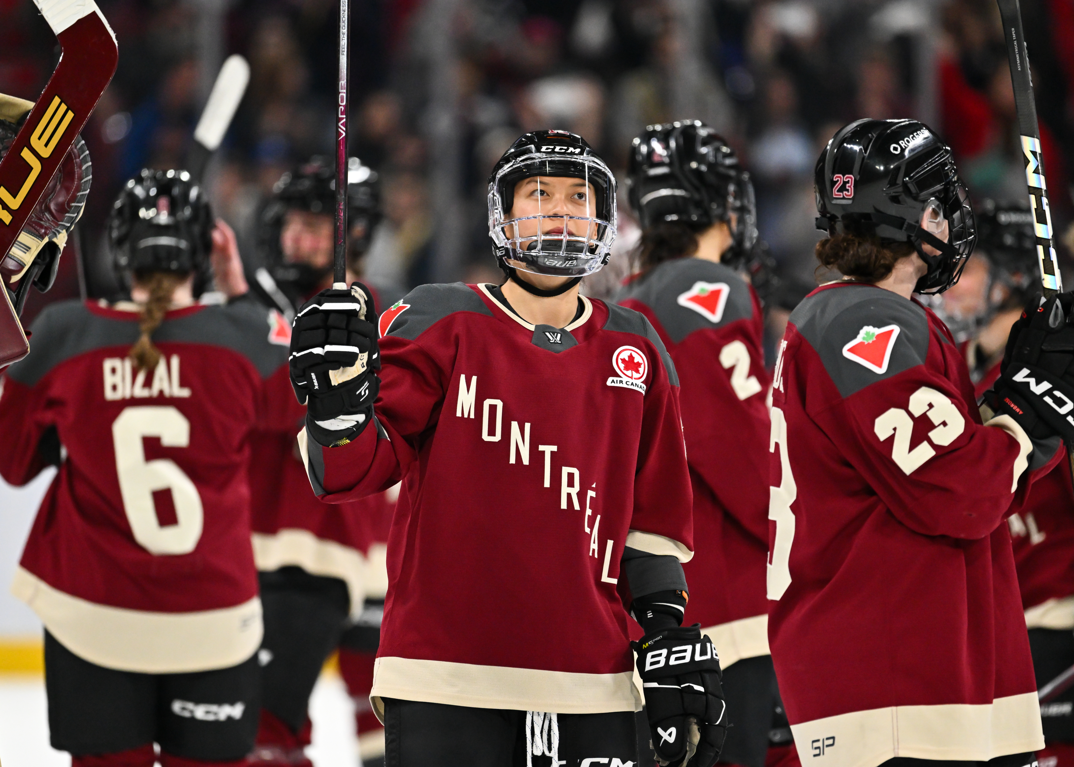 Hockey team members on the ice rink wearing Montreal jerseys, some with raised hockey sticks