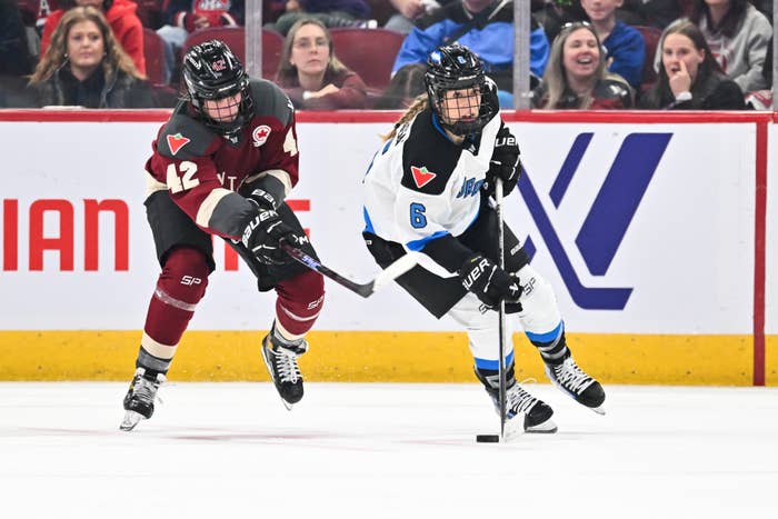 Two hockey players from opposing teams competing on the ice during a game