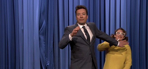 Jimmy Fallon and a guest are dancing joyfully behind a curtain on a stage