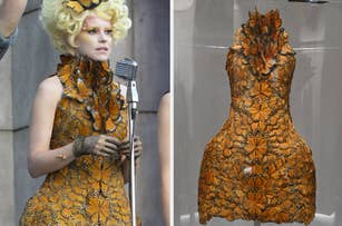 Effie Trinket character from "The Hunger Games" in butterfly dress next to the dress on display