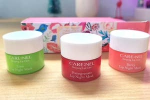 Three CARE:NEL lip masks on a surface, with packaging in the background