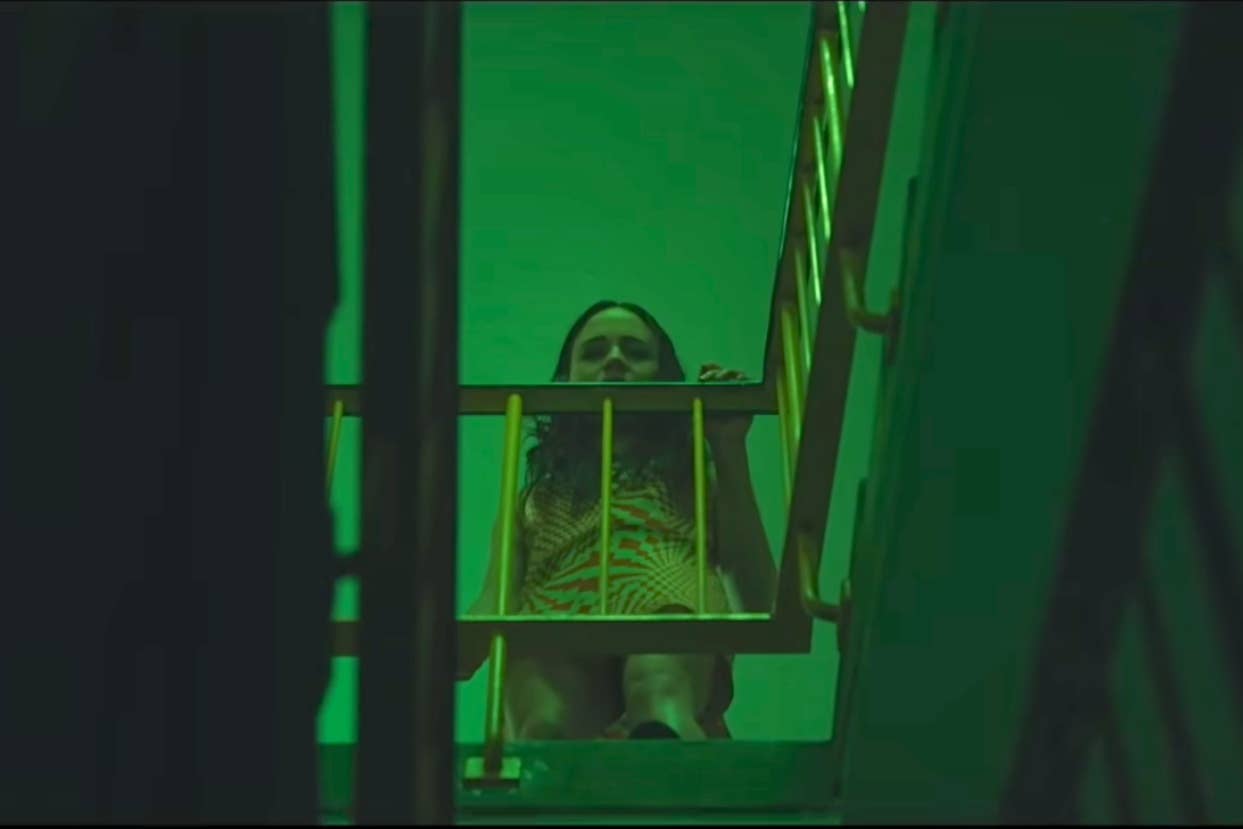 Person peering through a staircase with green lighting, creating a mysterious ambiance for an online intrigue