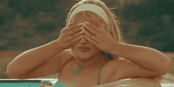 Mujer tapándose los ojos con las manos junto a la piscina