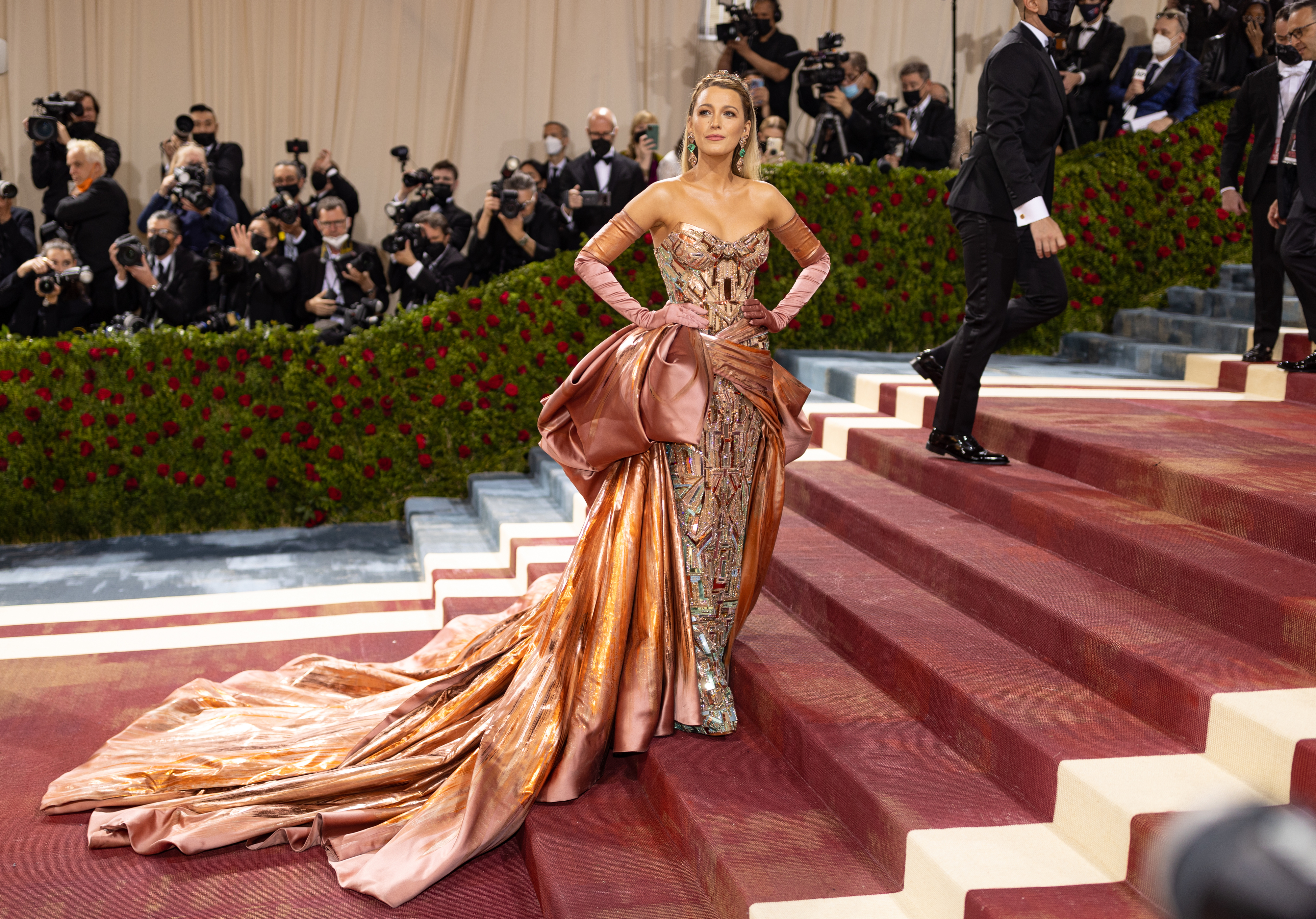 Blake Lively in a metallic dress with a long train and gloves on Met Gala steps,