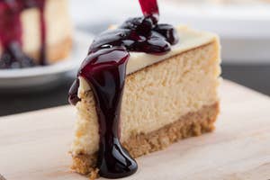 A slice of cheesecake with berry topping on a wooden board